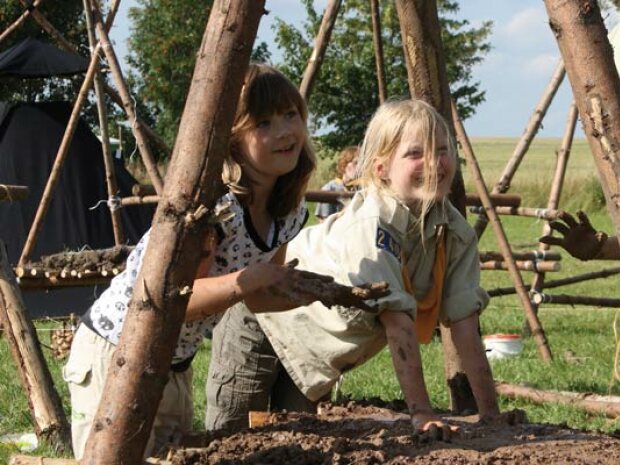 Kinder, die eine Feuerschale aus Lehm gebaut haben.